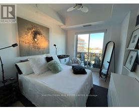 A bedroom with a bed, a mirror, and a ceiling fan.