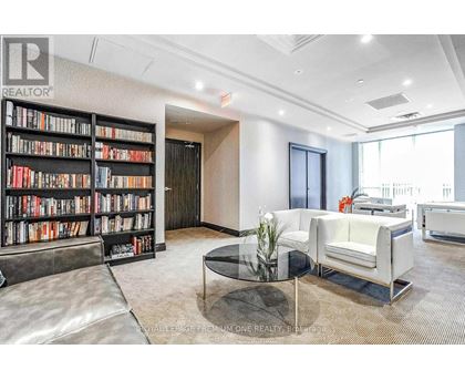 A living room with a glass coffee table and a bookshelf filled with books.