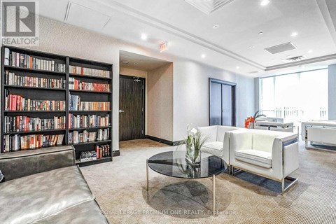 A living room with a glass coffee table and a bookshelf filled with books.
