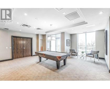A room with a pool table and chairs.