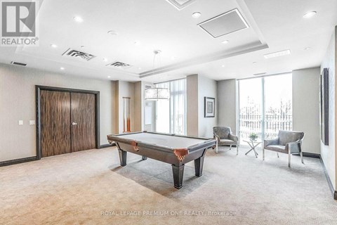 A room with a pool table and chairs.