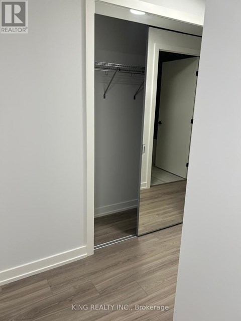 A white closet with a mirror and a wooden floor.