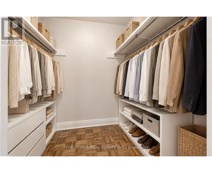 A well organized walk in closet with clothes hanging on shelves and drawers underneath.