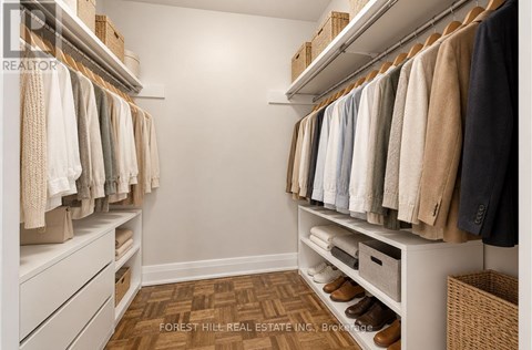 A well organized walk in closet with clothes hanging on shelves and drawers underneath.