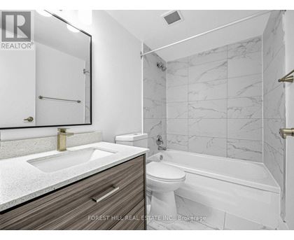 A bathroom with a marble tile wall and a white toilet.
