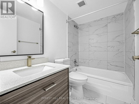 A bathroom with a marble tile wall and a white toilet.