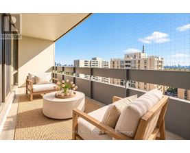 A balcony with a table and chairs overlooking a cityscape.