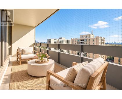 A balcony with a table and chairs overlooking a cityscape.