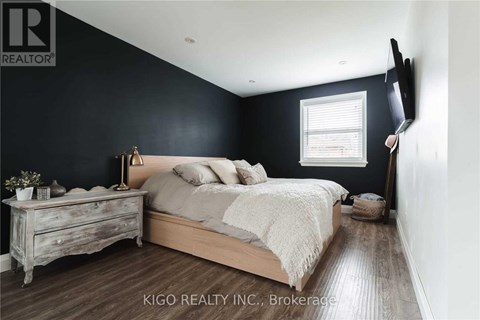A bedroom with a bed, nightstand, and a wall-mounted TV.