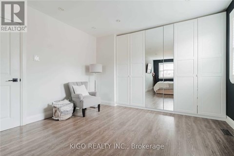 A spacious room with white walls and wooden flooring, furnished with a chair and a small table.