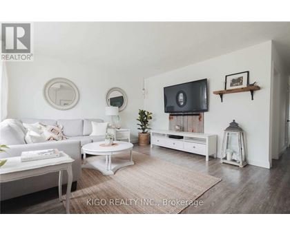 A living room with a white couch, a white coffee table, a white TV stand, and a white rug.