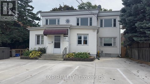 A white house with a red awning is for sale.