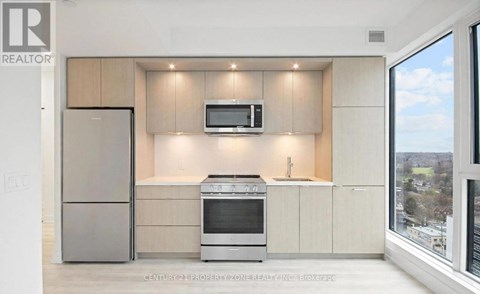 A modern kitchen with a refrigerator, oven, and microwave.
