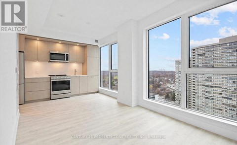 A spacious living room with a television and a large window overlooking a cityscape.