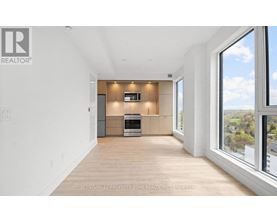 A spacious, well-lit room with a kitchen area and a large window overlooking a landscape.