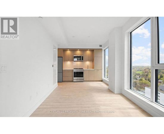 A spacious, well-lit room with a kitchen area and a large window overlooking a landscape.