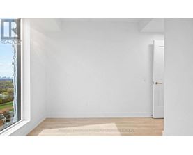 A white room with a door and a window overlooking a tree-filled landscape.
