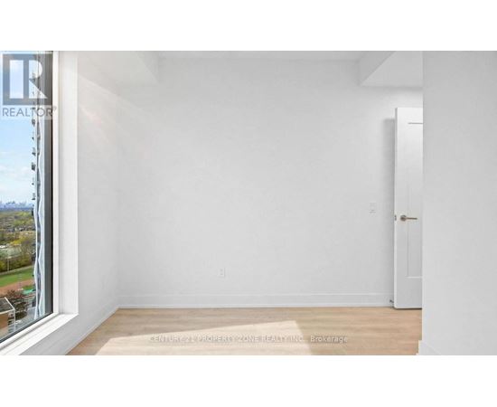 A white room with a door and a window overlooking a tree-filled landscape.