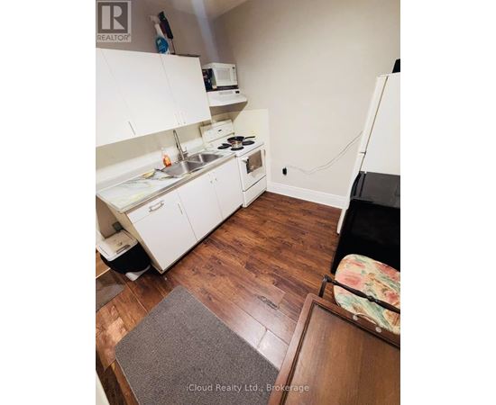 A kitchen with white cabinets and a wooden floor.