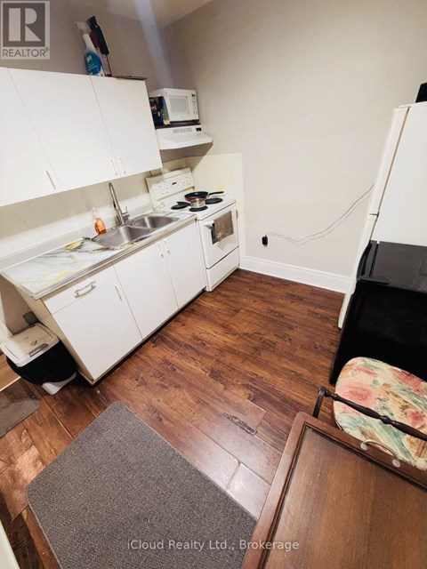 A kitchen with white cabinets and a wooden floor.