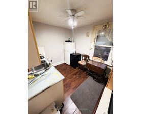 A kitchen with a refrigerator, sink, and a wooden floor.