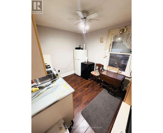 A kitchen with a refrigerator, sink, and a wooden floor.