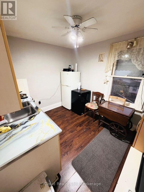 A kitchen with a refrigerator, sink, and a wooden floor.