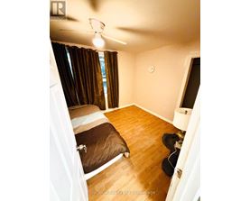 A bedroom with a bed, a ceiling fan, and a window with curtains.