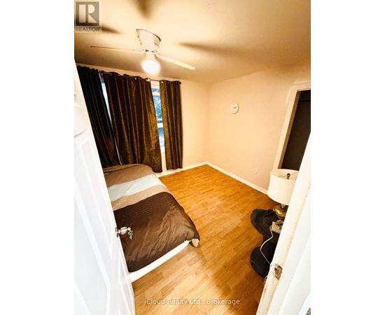 A bedroom with a bed, a ceiling fan, and a window with curtains.