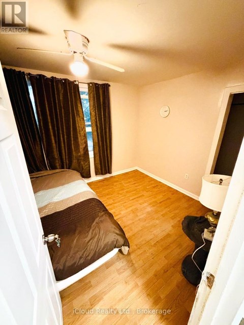 A bedroom with a bed, a ceiling fan, and a window with curtains.