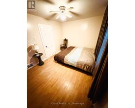 A bedroom with a bed, a lamp, and a ceiling fan.
