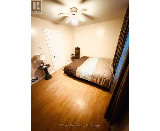 A bedroom with a bed, a lamp, and a ceiling fan.
