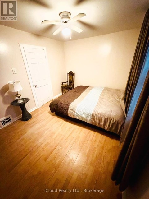A bedroom with a bed, a lamp, and a ceiling fan.