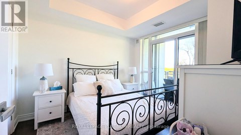 A bedroom with a black metal bed frame and white bedding.