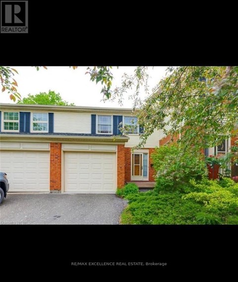A house with a garage and a tree in front.