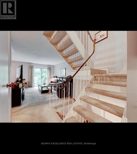 A staircase with a beige carpeted runner and white risers leads up to a balcony.