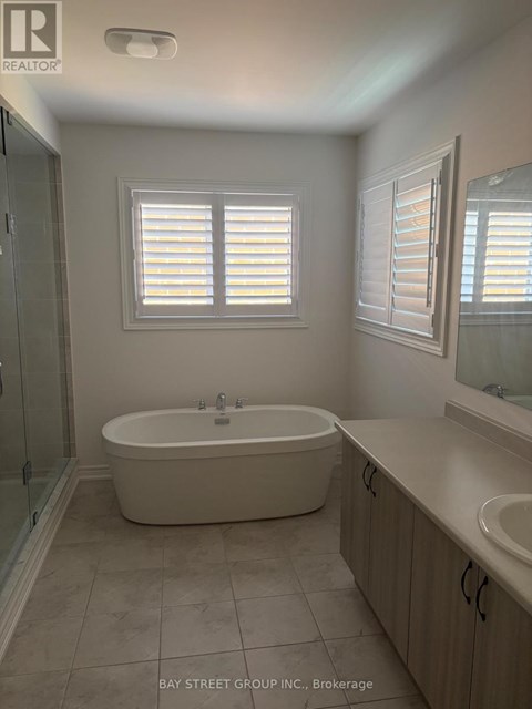 A white bathroom with a tub, sink and mirror.
