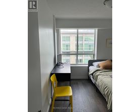 A bedroom with a bed, desk, and chair.