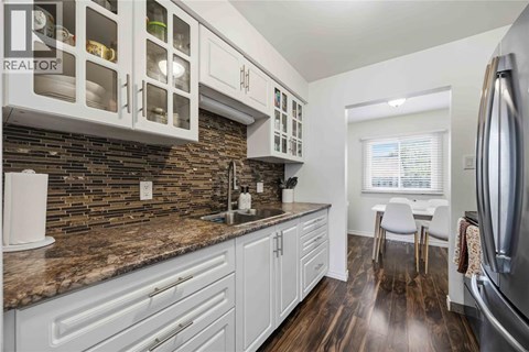 A kitchen with white cabinets and a granite countertop.