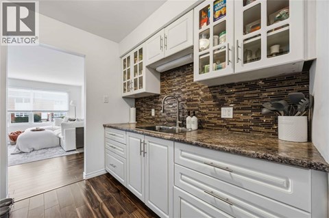 A kitchen with white cabinets and a stone backsplash.