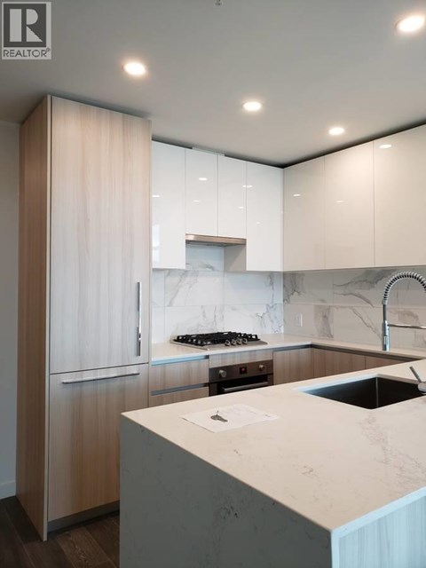 A modern kitchen with a marble countertop and wooden cabinets.