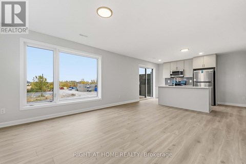 A spacious room with a bar area and a view of the outside through the windows.