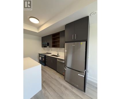 A modern kitchen with a refrigerator, microwave, and oven.
