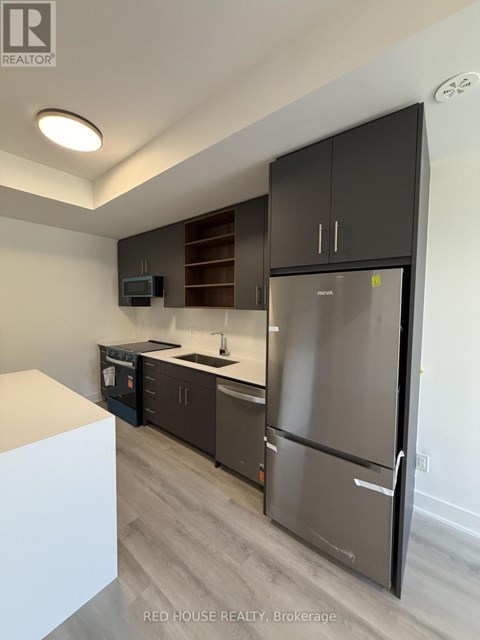 A modern kitchen with a refrigerator, microwave, and oven.