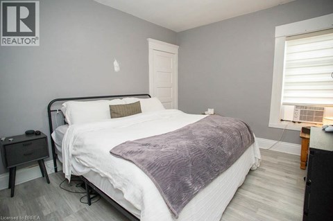 A bedroom with a bed, nightstand, and window.