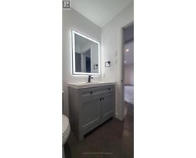 A bathroom with a sink, toilet and mirror.