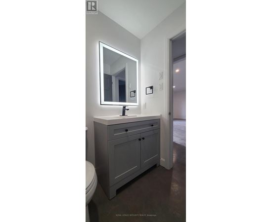 A bathroom with a sink, toilet and mirror.