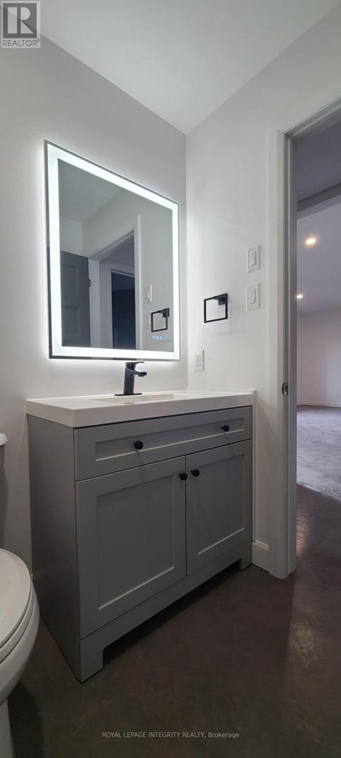 A bathroom with a sink, toilet and mirror.