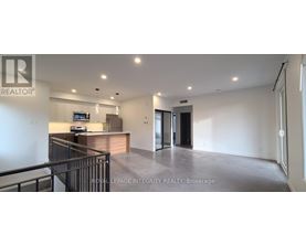 A spacious, empty living room with a kitchen area in the background.