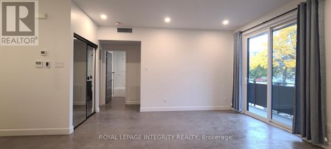 A spacious room with a sliding glass door leading to a balcony.